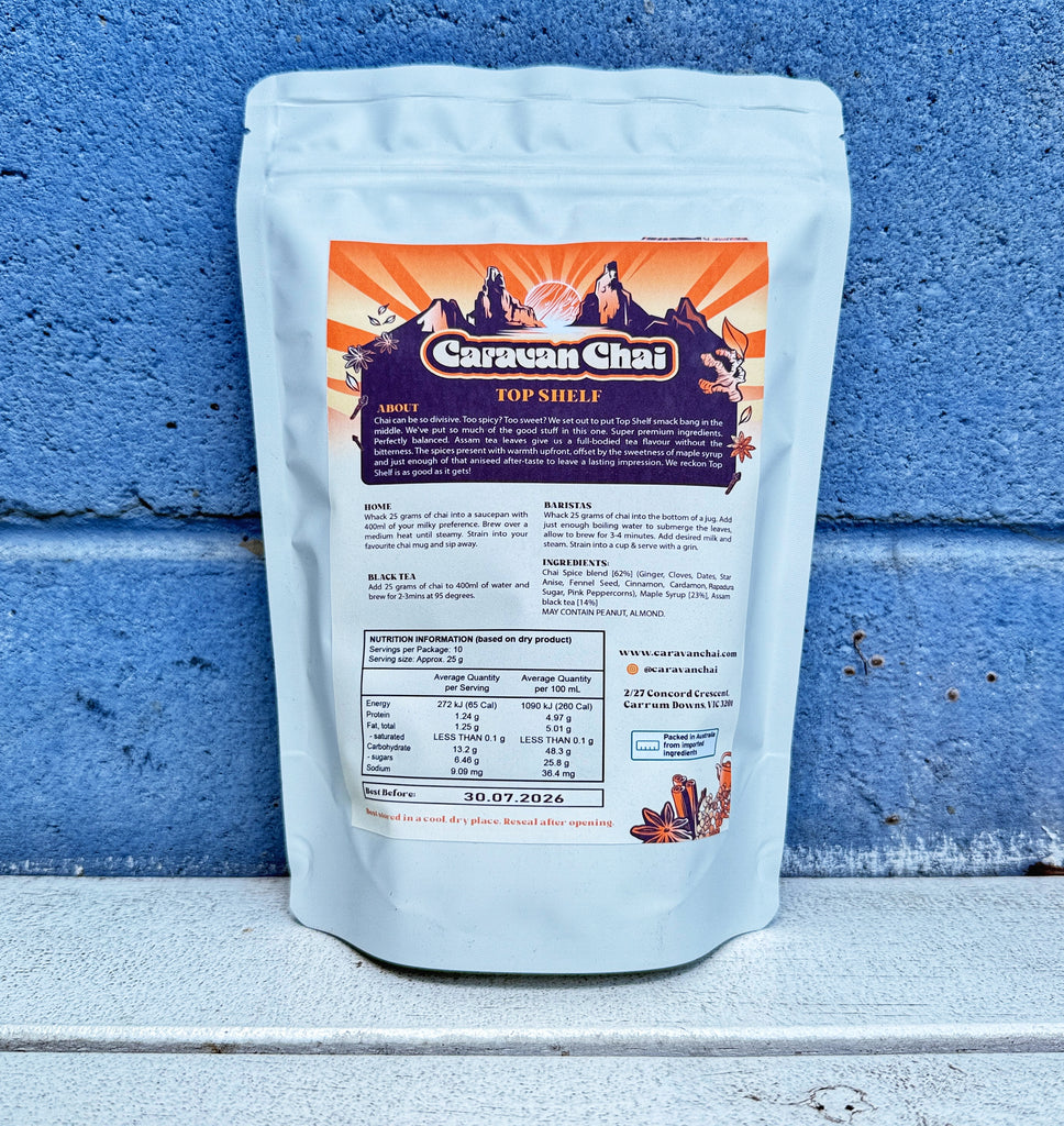 Caravan Chai packaging with label against a blue brick wall