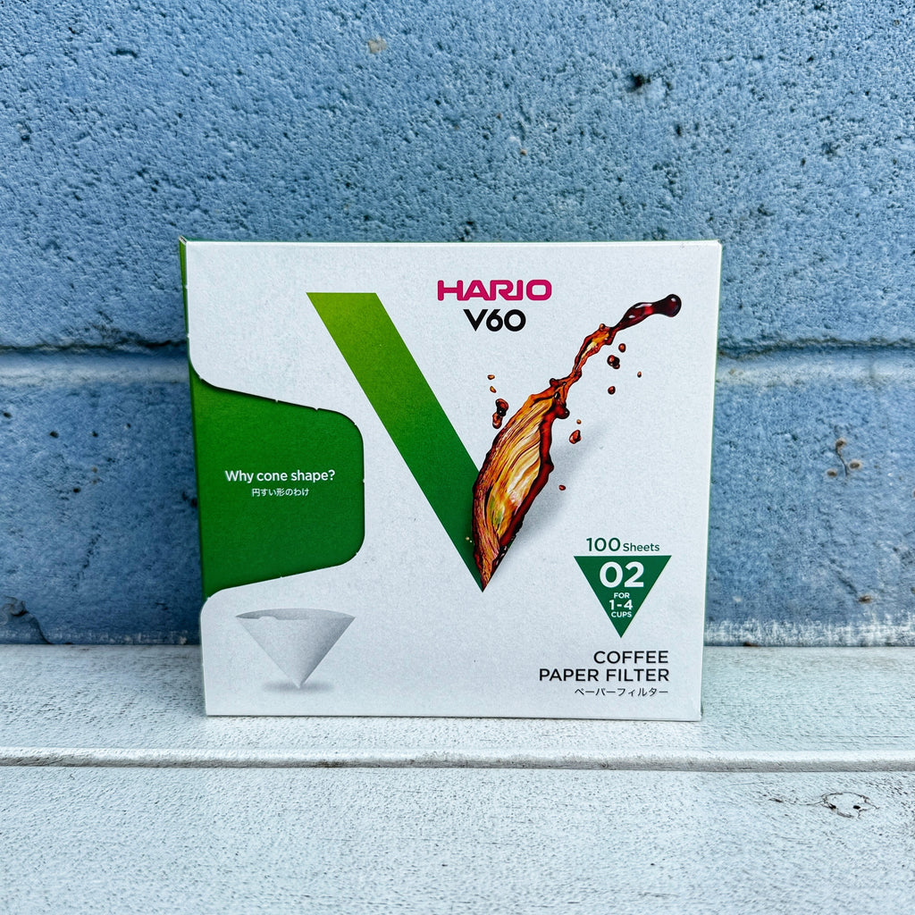 Hario V60 02 coffee paper filter box against a blue brick wall.