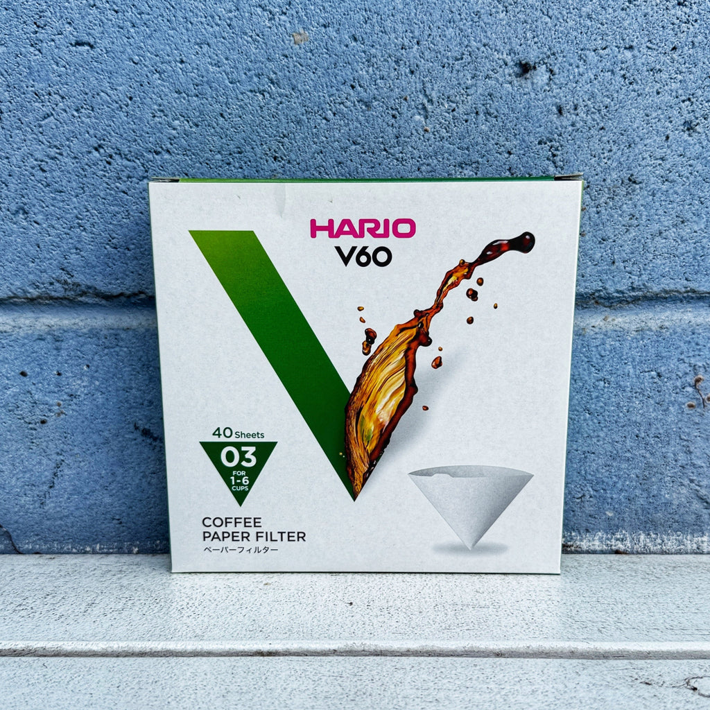 Hario V60 03 coffee paper filter box against a blue brick wall.