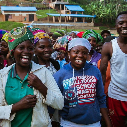 Group of people, including a woman in a blue hoodie with text, standing outdoors in a rural setting.